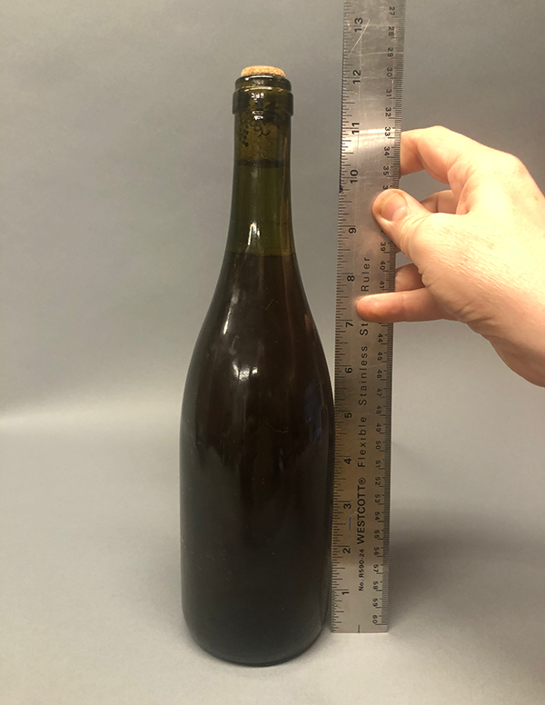 Photo of empty bottle with ruler next to it